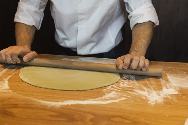 rolling out the dough with flour on a big table