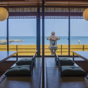 Japanese tatami room with low tables, floor cushions, and large windows overlooking the ocean at a luxury ryokan on Awaji Island.