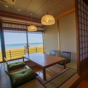 Traditional tatami dining room with low table, shoji doors, and ocean view at a luxury Japanese ryokan with private onsen on Awaji Island.