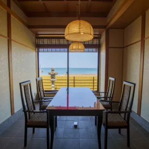 Japanese private dining room with wooden table, woven pendant lights, shoji‑style walls, and ocean view at a luxury ryokan on Awaji Island.