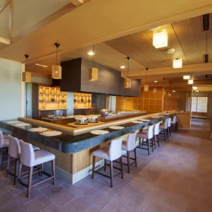 U‑shaped Japanese dining counter with stone surface, cushioned seating, and traditional wooden accents at a luxury ryokan with private onsen on Awaji Island.
