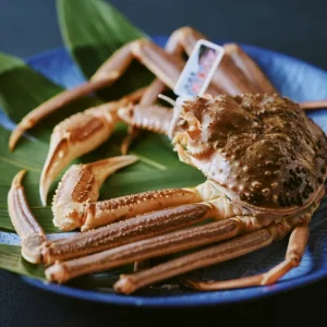 Whole premium crab presented on a blue ceramic plate with green leaves at a luxury Japanese ryokan with private onsen on Awaji Island.