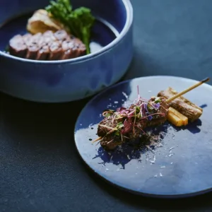 Artfully plated grilled meat and seasonal vegetables on ceramic dishes served at a luxury Japanese ryokan with private onsen on Awaji Island.