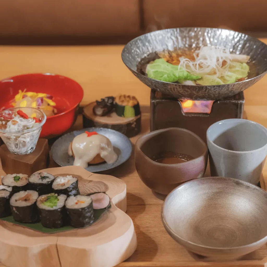 Artfully presented Japanese meal with hot pot, sushi, and seasonal plant‑based dishes at an Awaji Island Wellness & Zen Retreat.