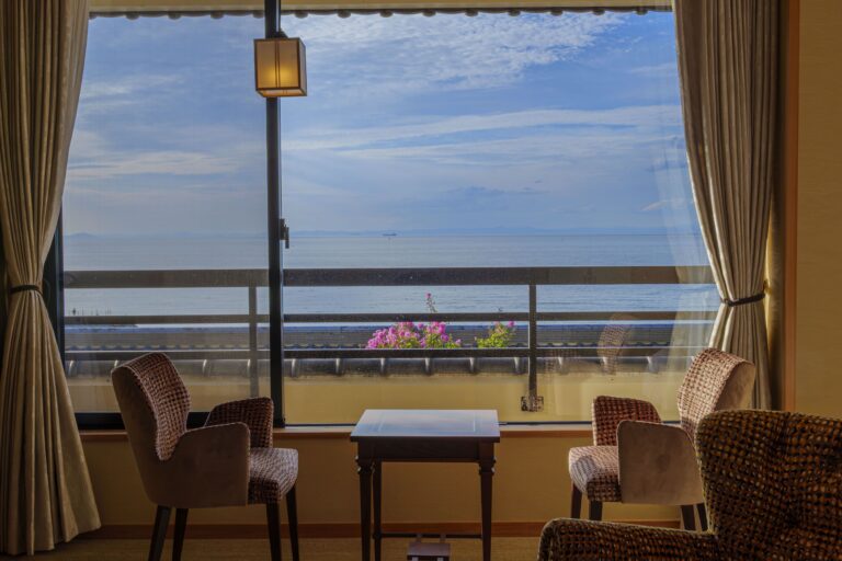 Seating area in superior Japanese-style room at Senshin Waho ryokan with large window and sunset ocean view over Seto Inland Sea