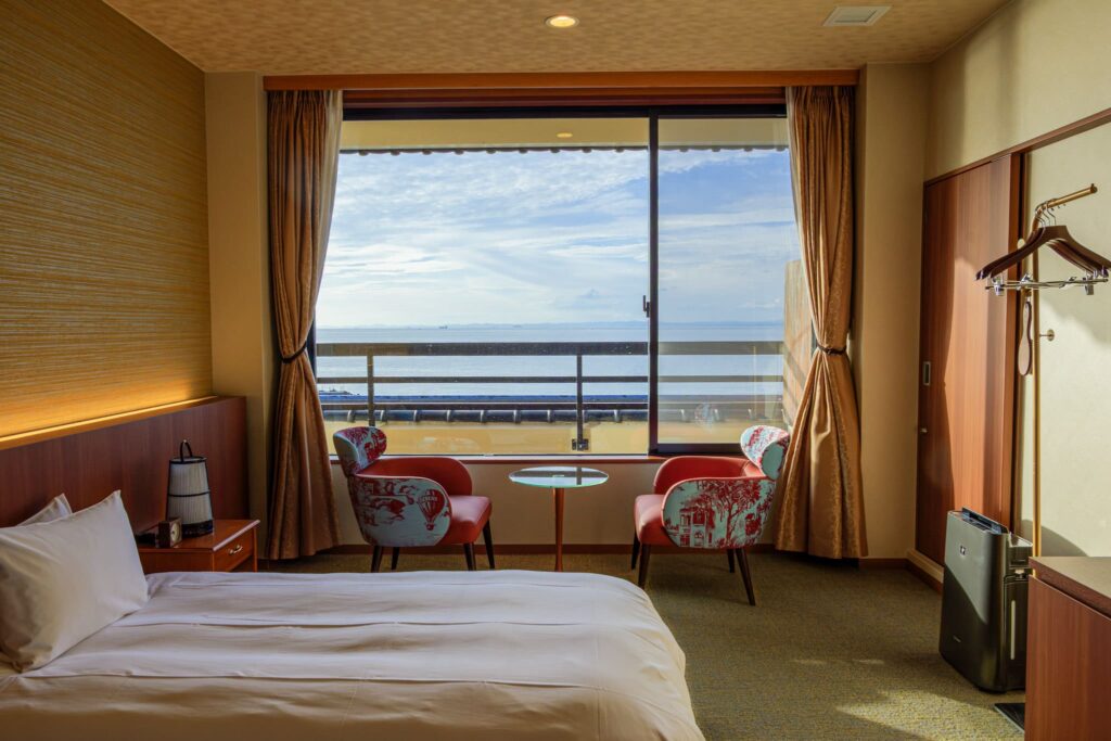 Standard Western-style room at Senshin Waho ryokan on Awaji Island with semi-double bed, seating area, cypress bath, and ocean view of the Seto Inland Sea