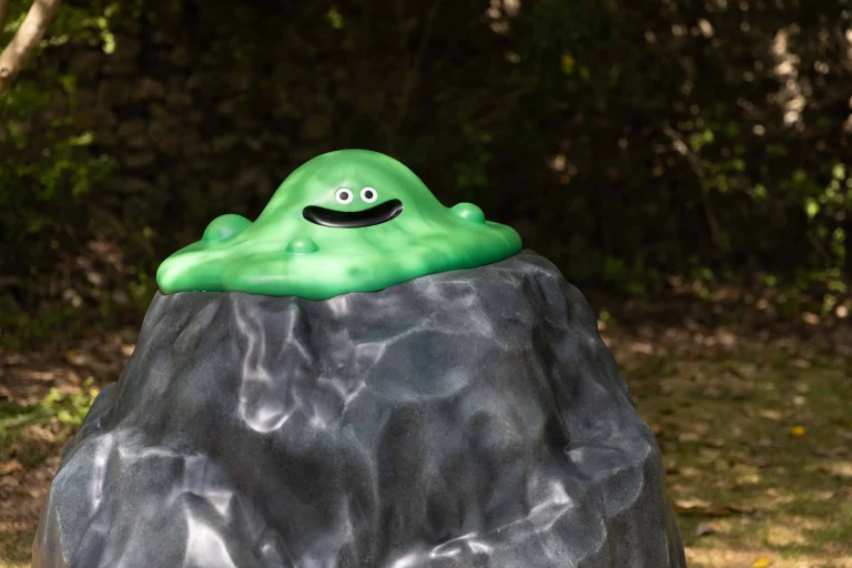 Green slime character sitting on rock at Dragon Quest Island in Nijigen no Mori Awaji Island