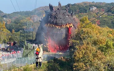Visitor flying on zipline into open Godzilla mouth at Nijigen no Mori Awaji Island